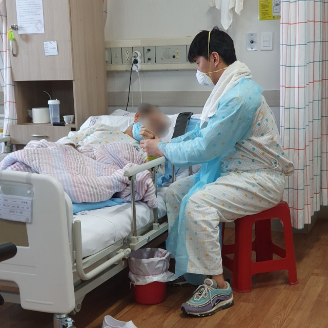 간병인 A(32) 씨가 24일 마스크와 위생복을 착용하고 환자를 돌보고 있다. 그는 지난 12일부터 뇌경색 환자 2명과 같이 머물며 24시간 이들을 간호하고 있다. A씨 제공