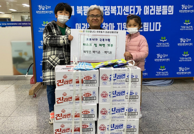 강원 동해시 북평동에 거주하는 백지훈·지원 남매가 지난 27일 북평동 행정복지센터를 찾아 최용봉 동장(가운데)에게 마스크 10장과 라면 20상자를 전달하고 있다. 연합뉴스