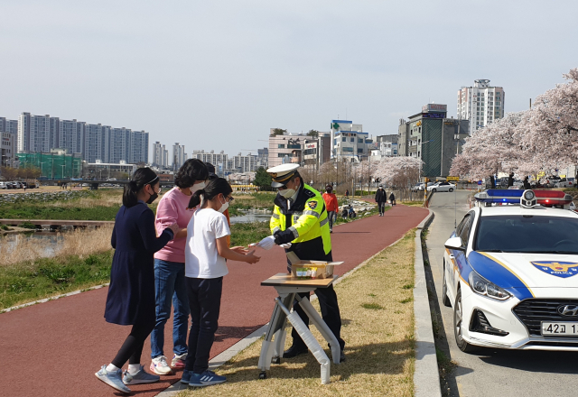 경산경찰서 소속 경찰관이 31일 남천변 산책길 시민들에게 핸드크림과 물티슈를 나눠 주면서 교통사고 예방 홍보를 하고 있다.