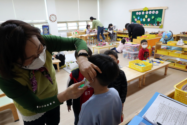 신종 코로나바이러스 감염증(코로나19) 사태가 장기화한 지난달 30일 광주 서구 광천초등학교병설유치원에서 긴급돌봄교실 교사가 원아 체온을 확인하고 있다. 연합뉴스