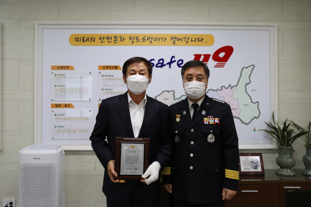 경북 청도소방서는 7일 옷에 불이 붙은 70대 이웃을 보고 적극적인 조치로 인명을 구조한 청도군 매전면 김기동(왼쪽) 이장에게 유공 표창을 수여했다. 청도소방서 제공