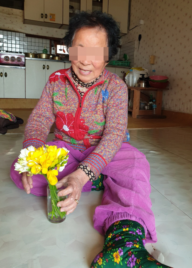 (사)안동자원봉사센터로부터 최근 후리지아 꽃다발을 받은 지역 한 어르신이 꽃을 보며 미소를 짓고 있다. (사)안동자원봉사센터 제공