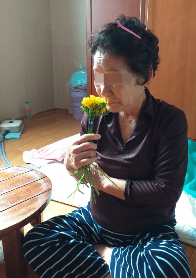 (사)안동자원봉사센터로부터 최근 후리지아 꽃다발을 받은 지역 한 어르신이 꽃 향기를 맡고 있다. (사)안동자원봉사센터