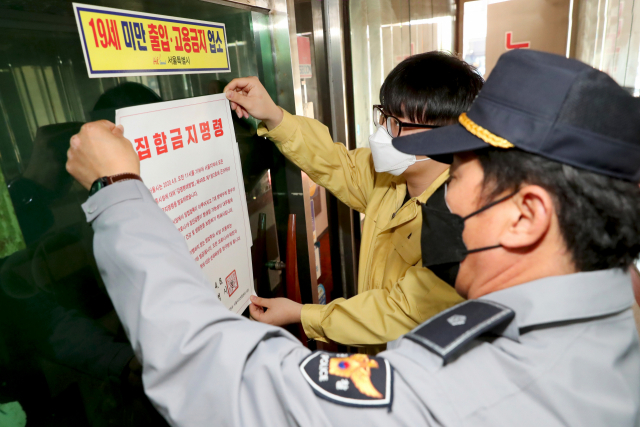 9일 성동구 보건소 관계자와 경찰이 서울 성동구의 한 유흥업소에 집합금지 명령서를 붙이고 있다. 서울 성동구는 서울시가 유흥업소에 대해 오는 19일까지 집합금지 명령을 내림에 따라 관내 유흥주점 22개소, 단란주점 41개소, 콜라텍 2개소 등 총 65개소에 대해 영업장 집합금지 고지와 함께 집합금지명령서를 부착했다고 밝혔다. [성동구 제공. 재판매 및 DB 금지] 연합뉴스