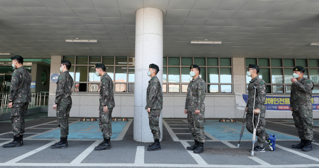 제21대 총선 사전투표가 시작된 10일 오전 강원 춘천시 신사우도서관에 마련된 사전투표소에 줄지은 군인들 사이로 목발을 짚은 장병이 소중한 표를 행사하고자 서 있다. 연합뉴스