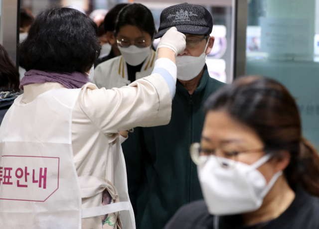 제21대 총선 사전투표 첫날인 10일 오전 부산진구 초읍동 사전투표소에서 한 유권자가 체온을 검사받고 있다. 연합뉴스