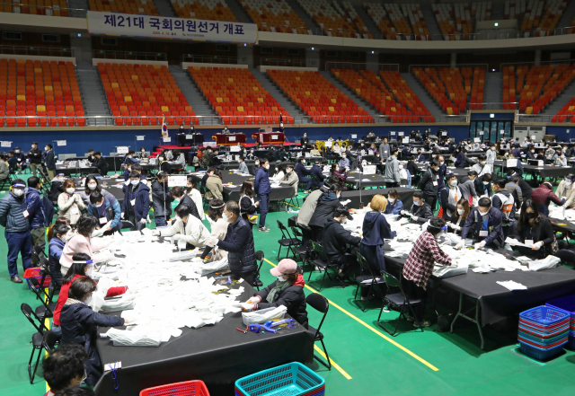제21대 국회의원선거 투표가 실시된 15일 저녁 광주 서구 개표소인 염주체육관에서 안전 마스크를 착용한 개표사무원들이 비례대표 투표용지를 수기 분류하고 있다. 연합뉴스