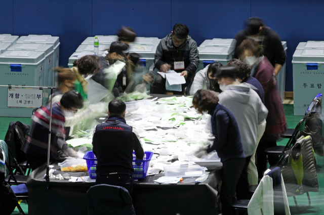 제21대 국회의원선거 투표가 실시된 15일 저녁 광주 서구 개표소인 염주체육관에서 개표사무원들이 투표용지를 분류하고 있다. 연합뉴스