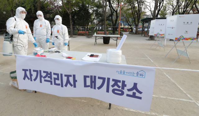 제21대 국회의원 선거일인 15일 오후 서울 송파구 잠실공원에 마련된 자가격리자 투표소에서 방호복을 입은 관계자들이 투표를 마무리한 뒤 공원을 방역하고 있다. 연합뉴스