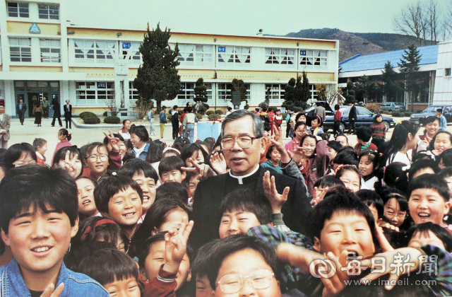 1993년 봄 김수환 추기경이 군위국민(초등)학교를 방문해 후배 어린이들에 둘러싸여 즐거운 시간을 보내고 있다. 추기경은 용대리에 살면서 보통학교 시절에 이 학교를 다녔다. 사진=(재)한국교회사연구소 제공