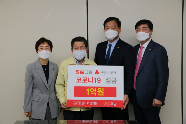 SM그룹 계열사인 SM(주)우방 송동근 사장(오른쪽) 등이 21일 사랑의열매에 코로나19 극복 성금 1억원을 전달하고 있다.