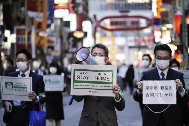 신종 코로나바이러스 감염증(코로나19) 확산으로 일본 전역에 긴급사태가 선포된 가운데 24일 도쿄의 대표적 유흥가인 신주쿠(新宿)구 가부키초 거리에서 마스크를 쓴 도쿄도 직원들이 시민들에게 외출 자제를 당부하고 있다. 연합뉴스