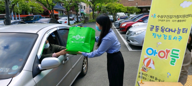 대구 수성구건강가정‧다문화가족지원센터 직원이 차량 안에 있는 주민에게 무료대여 장난감을 전달하고 있다. 수성구청 제공