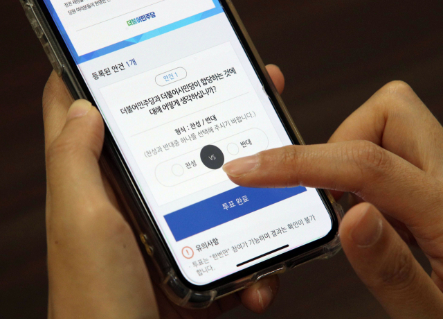 7일 오전 국회에서 한 더불어민주당 당원이 스마트폰으로 더불어민주당-더불어시민당 합당 여부를 묻는 권리당원 투표를 하고 있다. 연합뉴스