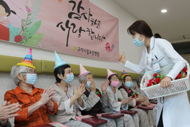 구미시립노인요양병원 직원들이 코로나19로 면회가 금지된 보호자를 대신해 입원 어르신들에게 카네이션 달아드리기 행사를 하고 있다. 구미대 제공