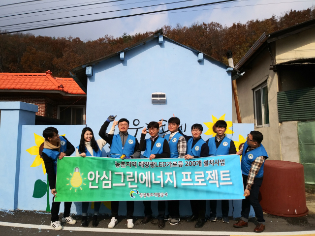경상북도개발공사가 추진하는 안심그린에너지 사업은 농촌지역 어두운 골목길을 태양광 LED벽부착등 기부사업으로 큰 호응을 얻고 있다. 공사 직원들이 봉사활동 후 부착등 밑에서 기념촬영을 하고 있다. 경북개발공사 제공