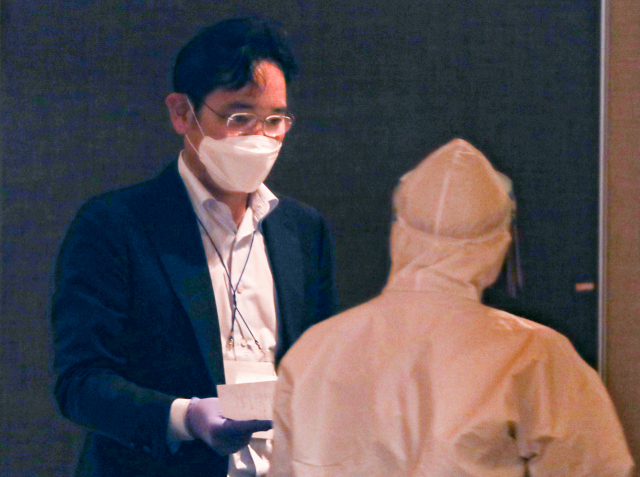 중국 시안 반도체 공장 방문을 마치고 김포공항을 통해 귀국한 이재용 삼성전자 부회장이 19일 오후 김포공항 인근 대기 장소에서 코로나19 검사를 받기 전 문진표를 작성해 제출하고 있다. 연합뉴스