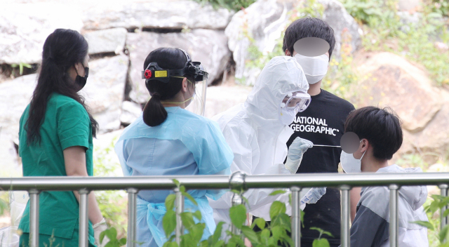 오성고등학교 3학년 학생 1명이 코로나19 확진 판정을 받은 27일 오전 대구 수성구 오성고등학교에서 한 학생이 보건소 관계자로부터 검체채취를 받고 있다. 김영진 기자 kyjmaeil@imaeil.com