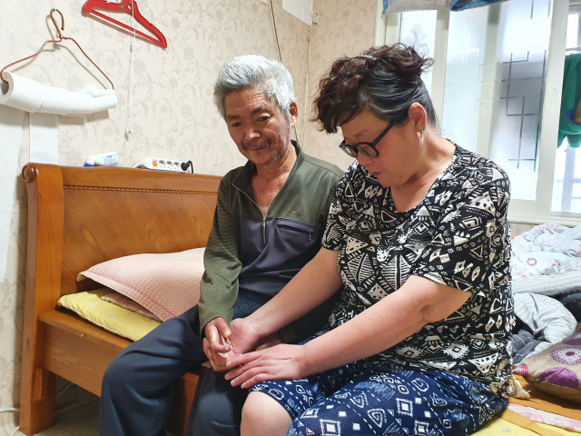 아내 장명자(가명‧49) 씨가 남편 김창석(가명‧60) 씨의 움직이지 않는 손을 멍하니 바라보고 있다. 배주현 기자