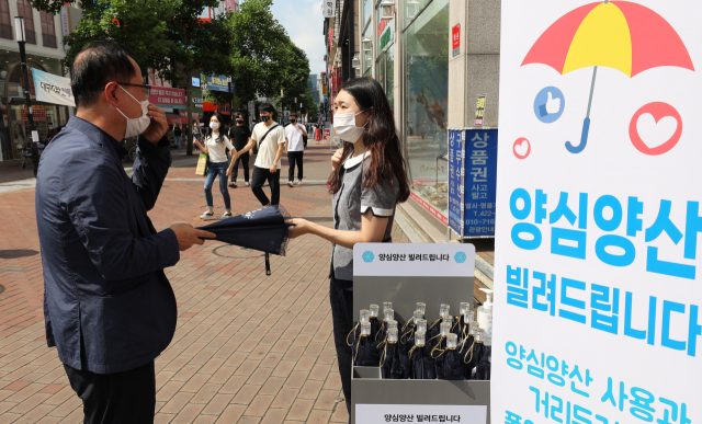 19일 오후 대구 중구 동성로 광장에 배치된 양심양산을 한 시민이 빌려가고 있다. 양심양산은 대구시가 폭염 극복과 코로나19 예방을 위해 생활 속 거리두기 실천의 일환으로 동성로, 김광석길, 도시철도 3호선 청라언덕역 등 9곳에 설치했다. 시민 누구나 대여할 수 있다. 김영진 기자 kyjmaeil@imaeil.com