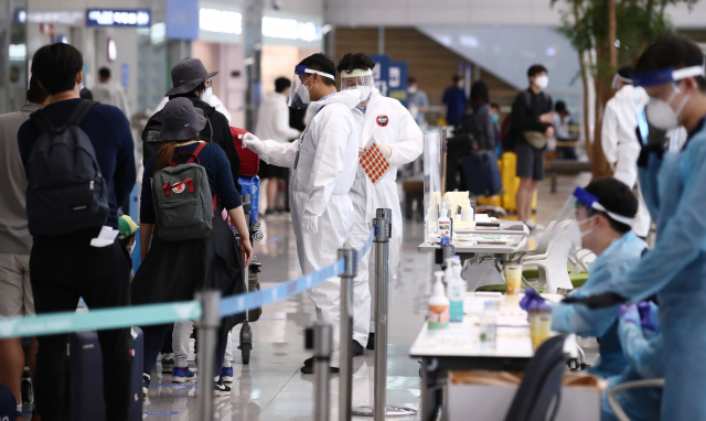 지난 20일 오후 인천국제공항 제2여객터미널에서 네덜란드 암스테르담 등에서 온 입국자들이 방역 관계자의 안내를 받으며 입국장을 빠져나가고 있다. 연합뉴스