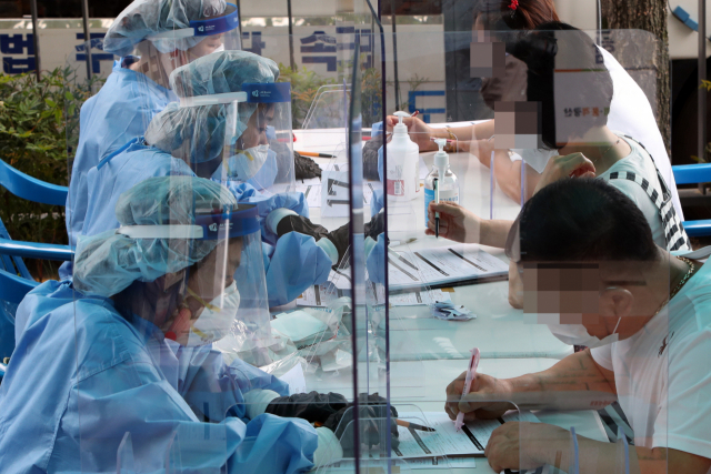 7일 오후 광주 광산구 신창동 행정복지센터에 마련된 코로나19 간이 선별진료소에서 시민이 진단검사 서류를 작성하고 있다. 연합뉴스