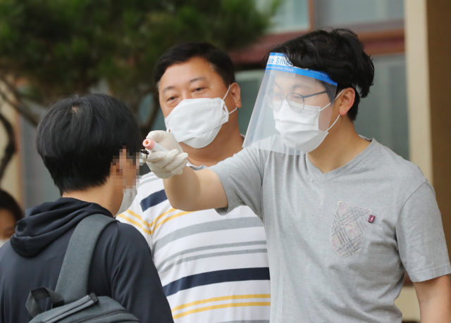 11일 오전 광주 서구의 한 중학교에 마련된 국가직 공무원 9급 필기시험장에서 한 수험생이 체온을 재고 있다. 최근 코로나19 확산세가 이어진 광주에서는 이날 1만2천121명이 지원한 국가직 공무원 9급 필기시험이 27개 시험장, 654개 시험실에서 치러진다. 연합뉴스