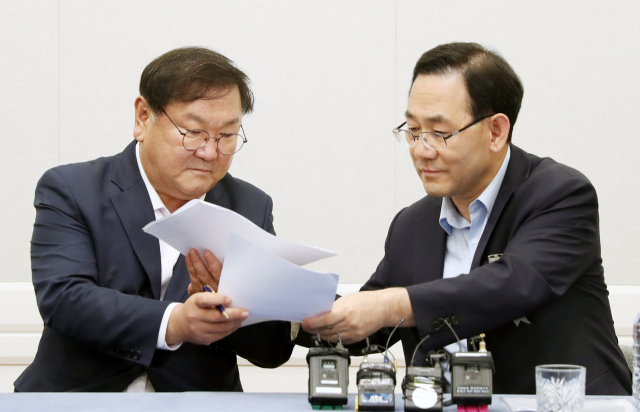 더불어민주당 김태년 원내대표와 미래통합당 주호영 원내대표가 14일 오후 서울 여의도 국회에서 개원식등 7월 임시국회 일정에 합의한 뒤 서명을 위해 합의문을 교환하고 있다. 연합뉴스