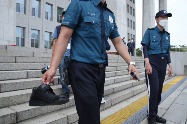 국회 경비경찰이 16일 오후 정모씨가 국회 개원식 참석을 마치고 돌아가는 문재인 대통령에게 던진 신발을 수거하고 있다. 연합뉴스