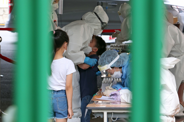 18일 오후 광주 서구 치평동 계수초등학교 주차장에 마련된 이동선별진료소에서 의료진이 울음을 터뜨리는 아이를 달래고 있다. 방역 당국은 재학생인 남매가 코로나19 확진 판정을 받아 계수초 전교생에 대해 전수검사를 하기로 했다. 연합뉴스