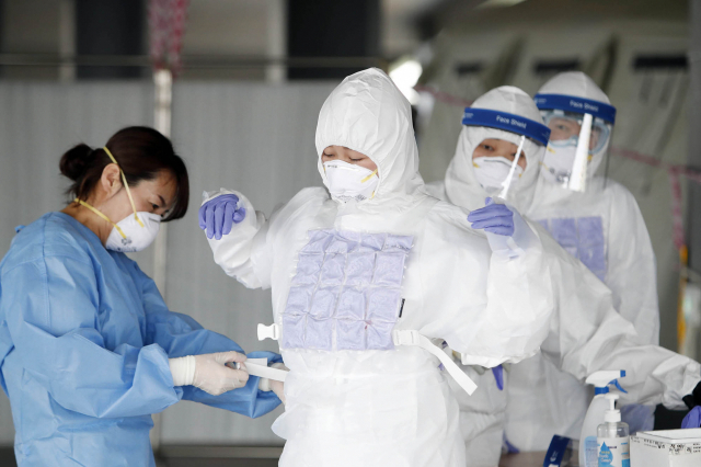 지난 17일 오후 광주 북구보건소 선별진료소가 마련된 효죽공영주차장에서 코로나19 검사를 담당하는 의료진이 무더위에 냉조끼를 착용하고 있다. 연합뉴스