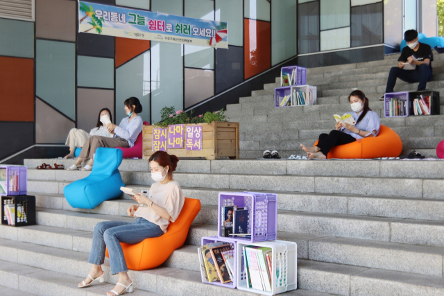 주민들이 범어도서관 앞마당에 조성된 우리동네 그늘 쉼터의 빈백 쇼파에 앉아 책을 읽으며 휴식하고 있다. 수성구청 제공