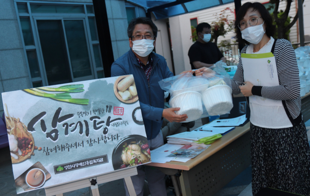 박홍열 영천시장애인종합복지관장이 지역 초·중·고교생 가족봉사단원에게 취약계층 장애인가구에 전달할 삼계탕을 나눠주고 있다. 영천시장애인종합복지관 제공