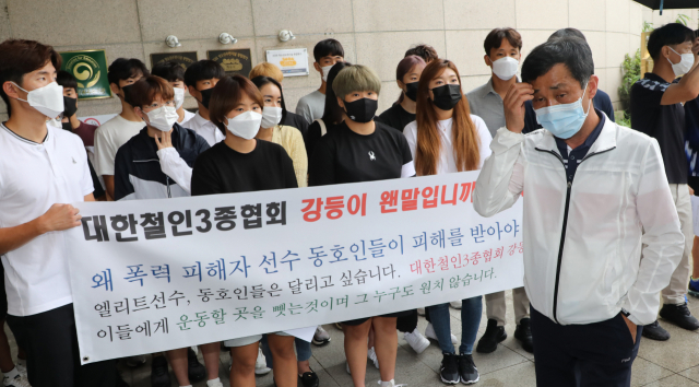 고 최숙현 선수 아버지 최영희 씨가 29일 대한체육회 이사회가 열리는 송파구 올림픽파크텔 앞에서 협회 강등에 반대하는 철인3종경기 실업팀 선수들 앞을 지나고 있다. 최영희 씨는 