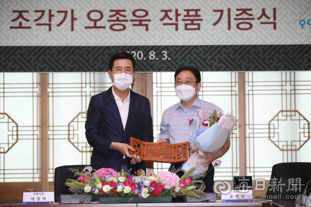 국내 1세대 철 용접 조각가인 고(故) 오종욱 선생의 작품 기증식을 맞아 이강덕 포항시장(왼쪽)이 오종욱 선생의 자제인 오석진 씨에게 명예시민증을 전달하고 있다. 포항시 제공