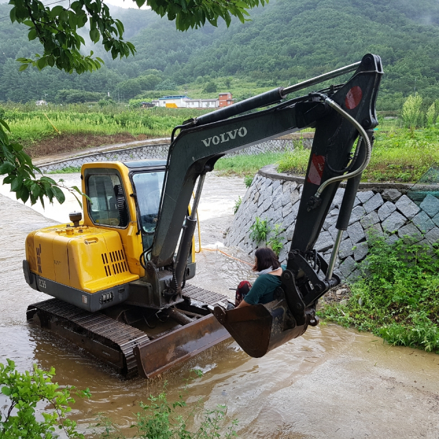 오전 9시 20분쯤 청송군 부동면 한 하천에서 불어난 계곡물로 고립된 시민이 포크레인으로 구조돼 옮겨지고 있다. 경북소방본부 제공