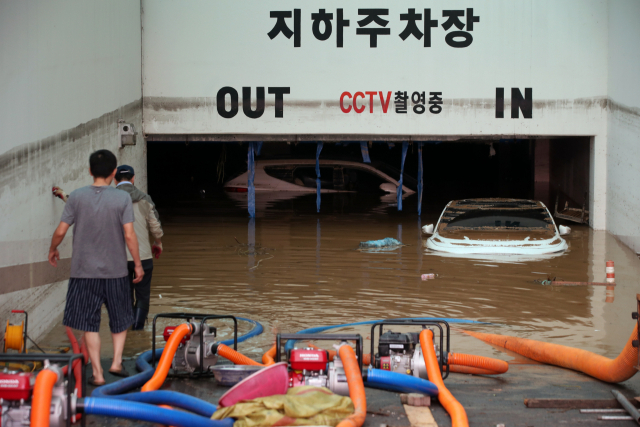 9일 오전 광주 북구 신안동 한 아파트에서 전날 집중호우로 신안교가 범람하며 침수된 지하주차장의 배수 작업이 이틀째 이루어지는 가운데 물에 잠긴 일부 차량이 보인다. 연합뉴스