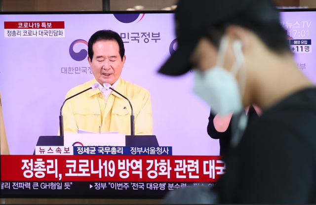 18일 오후 서울역 대합실에서 시민이 정세균 국무총리 코로나19(신종 코로나바이러스 감염증) 방역 강화 관련 대국민 담화 발표를 시청하고 있다. 연합뉴스