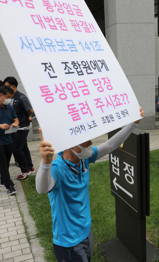20일 서초동 대법원 앞에서 기아차 노조원이 통상임금 승소 기자회견 후 피켓을 들고 있다. 이날 대법원은 기아차 노조원들이 정기 상여금 등이 통상임금에 해당한다며 낸 임금 청구 소송 상고심에서 원고 일부 승소로 판결한 원심을 확정했다. 연합뉴스