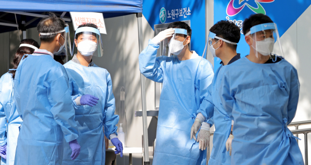 25일 서울 노원구보건소 코로나19 선별진료소에서 의료진이 모여 이야기를 나누고 있다. 연합뉴스