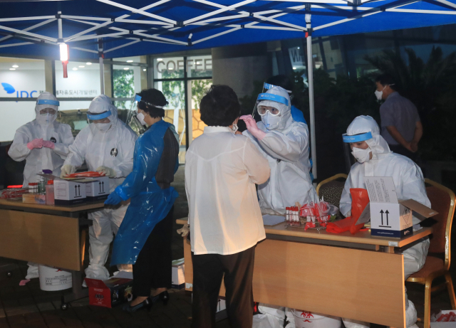 25일 오후 제주국제자유도시개발센터(JDC) 주차장에 마련된 선별진료소에서 JDC 직원이 코로나19 검사를 받고 있다. 이날 JDC 내에서 코로나19 확진자 2명이 발생했다. 연합뉴스