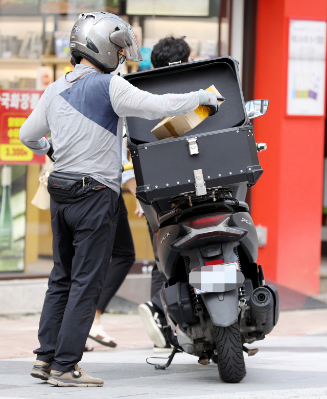 지난 4일 오후 대구 중구 동성로에서 한 배달 라이더가 고객에게 전달할 물품을 꺼내 이동하고 있다. 코로나19 재확산으로 배달 주문량이 급증하면서 배달원 수급에 어려움이 이어지고 있다. 김영진 기자 kyjmaeil@imaeil.com