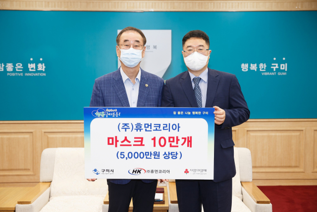 경북 구미산단 내 모동환(오른쪽) ㈜휴먼코리아 대표이사가 장세용 구미시장에게 마스크 10만 장을 기탁하고 있다. 구미시 제공
