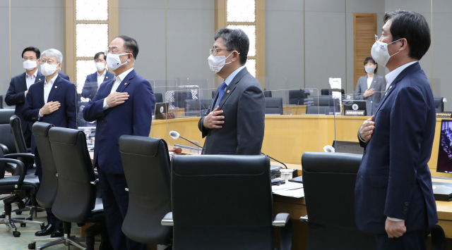 홍남기 경제부총리 겸 기획재정부 장관(오른쪽 세번째)과 국무위원들이 15일 오전 세종시 정부세종청사에서 서울과 영상으로 연결해 열린 정세균 국무총리 주재 국무회의에 참석해 국기에 경례하고 있다. 연합뉴스