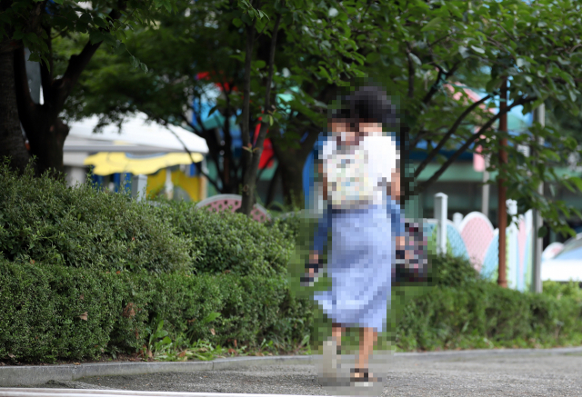 정부의 사회적 거리 두기 2단계 격상에 따라 어린이집 개원이 연기된 지난 8월 18일 서울의 한 어린이집에 긴급돌봄 지원을 받기 위해 부모와 어린이가 입장하고 있다. 서울시는 그동안 휴원해온 어린이집 5천420곳을 이날부터 다시 열기로 했던 계획을 철회했다. 보건복지부의 어린이집 휴원 권고에 따라 별도 명령 시까지 개원을 연기한다. 연합뉴스