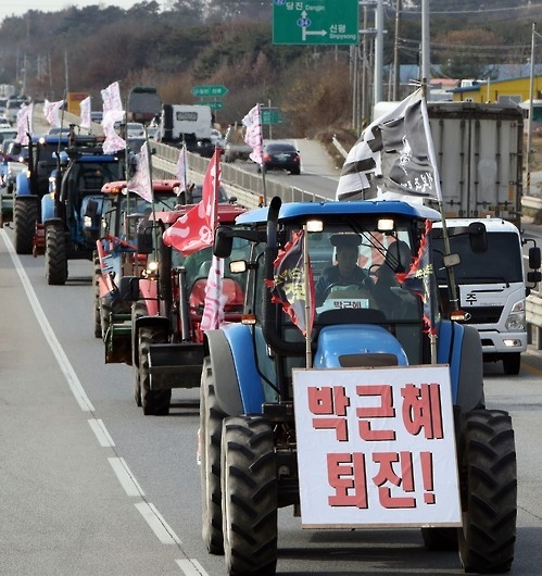 2016년 11월 23일 농민들이 박근혜 대통령 퇴진을 요구하는 문구를 적은 플래카드를 단 트랙터를 몰고 있다. 이들은 당시 주말에 서울 광화문에서 열릴 예정이었던 촛불집회에 참석하고자 도로를 달렸다. 연합뉴스