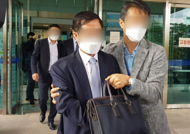 식품업체 수사를 무마한 혐의를 받는 대구경찰청 소속 경무관(가운데 짙은 색 양복)이 25일 오후 대구지방법원 서부지원에서 구속영장실질심사를 받고 나오고 있다. 연합뉴스