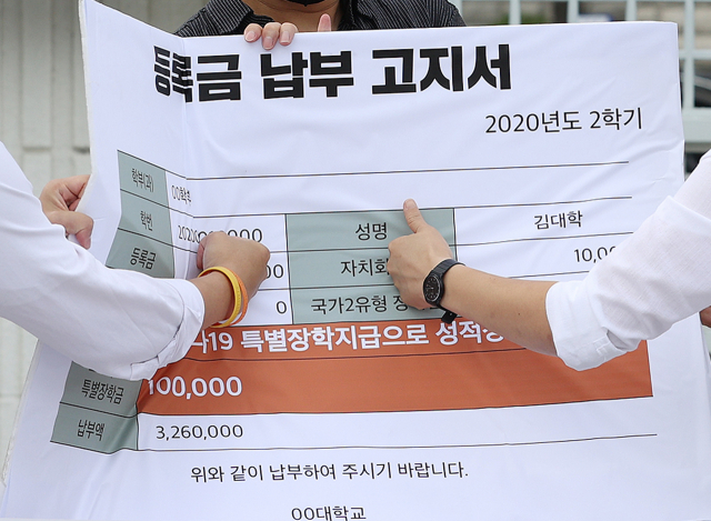 청년진보당 관계자들이 지난달 10일 오전 정부서울청사 앞에서 열린 코로나시대 대학생 권리찾기 운동 선포 기자회견에서 등록금 100만원 상한제 추진 및 등록금 반환에 대한 교육부의 관리감독과 기준 마련을 촉구하며 등록금 납부 고지서를 주먹으로 치는 퍼포먼스를 하고 있다. 연합뉴스