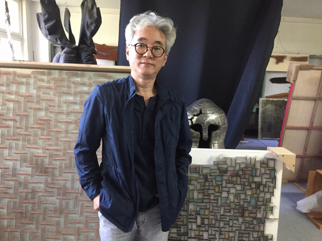 15년째 작업실로 사용해온 한 폐교에서 손파 작가가 그의 입체 투구 작품과 평면 작품 앞에서 포즈를 취하고 있다.