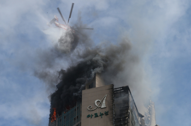 8일 오후 울산시 남구 한 주상복합아파트에서 난 화재가 9일 오전까지 꺼지지 않아 헬기가 동원돼 진화 작업을 하고 있다. 연합뉴스